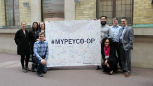 Students and staff posing with a large poster. The poster has the hashtag #mypeyco-op