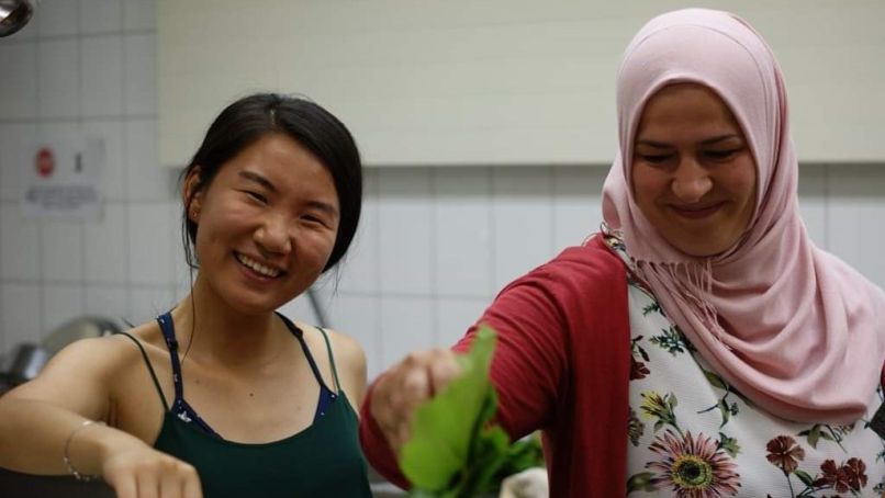 Two students smiling and cooking together